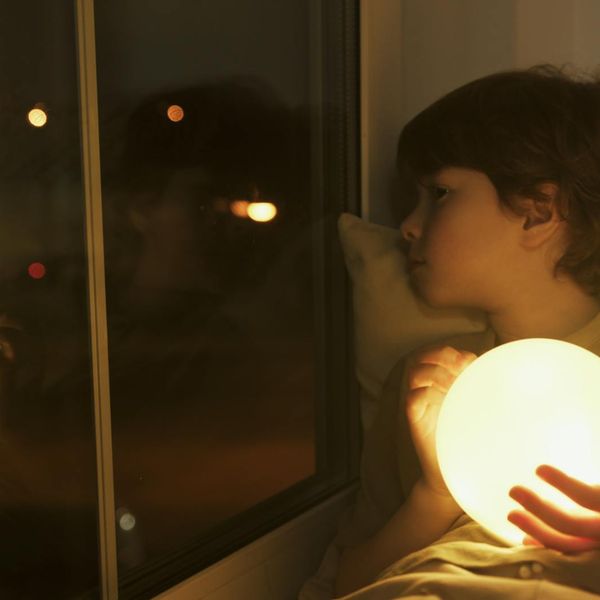 Person stretching gently indoors, with soft light creating a peaceful atmosphere.